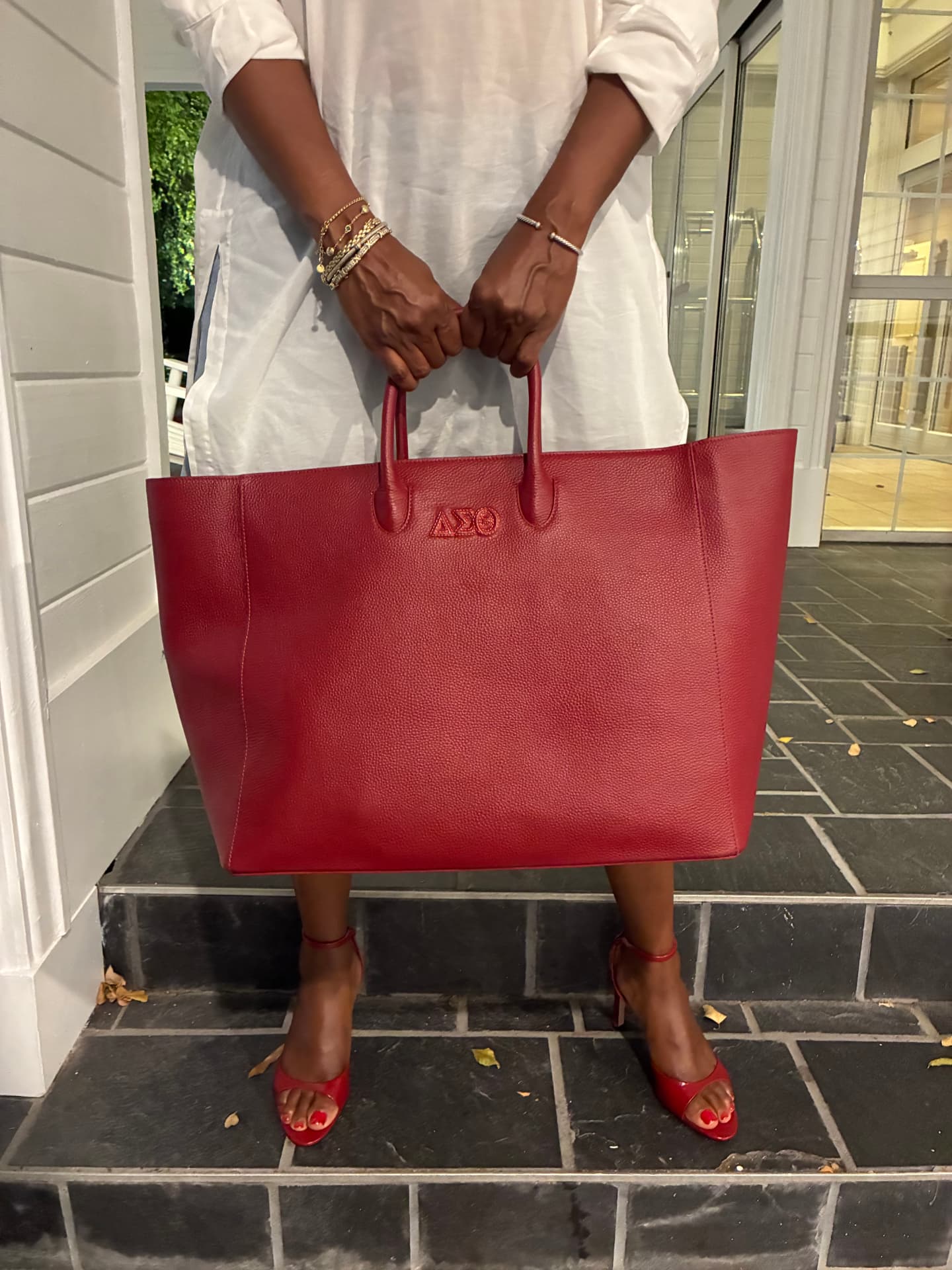 Woman holding the Signature Red Tote in front of her.
