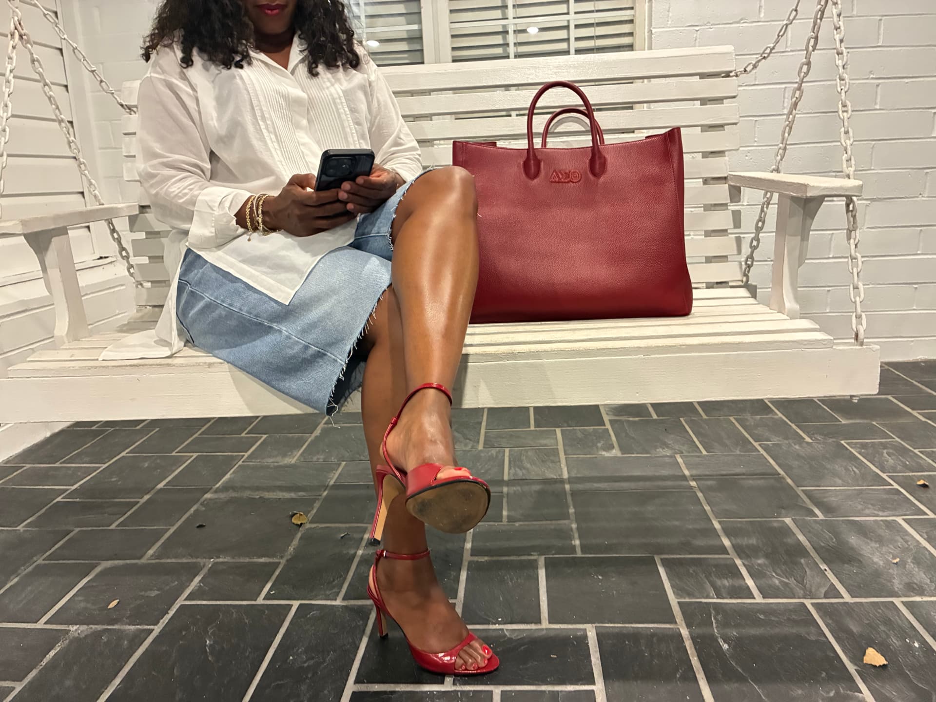 Woman seated beside the Signature Red Tote.